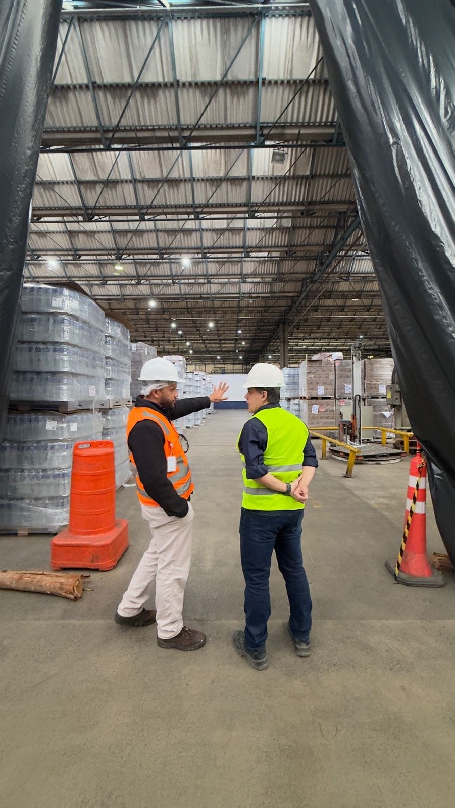 Dois engenheiros da EMR conversam durante vistoria em um galpão industrial